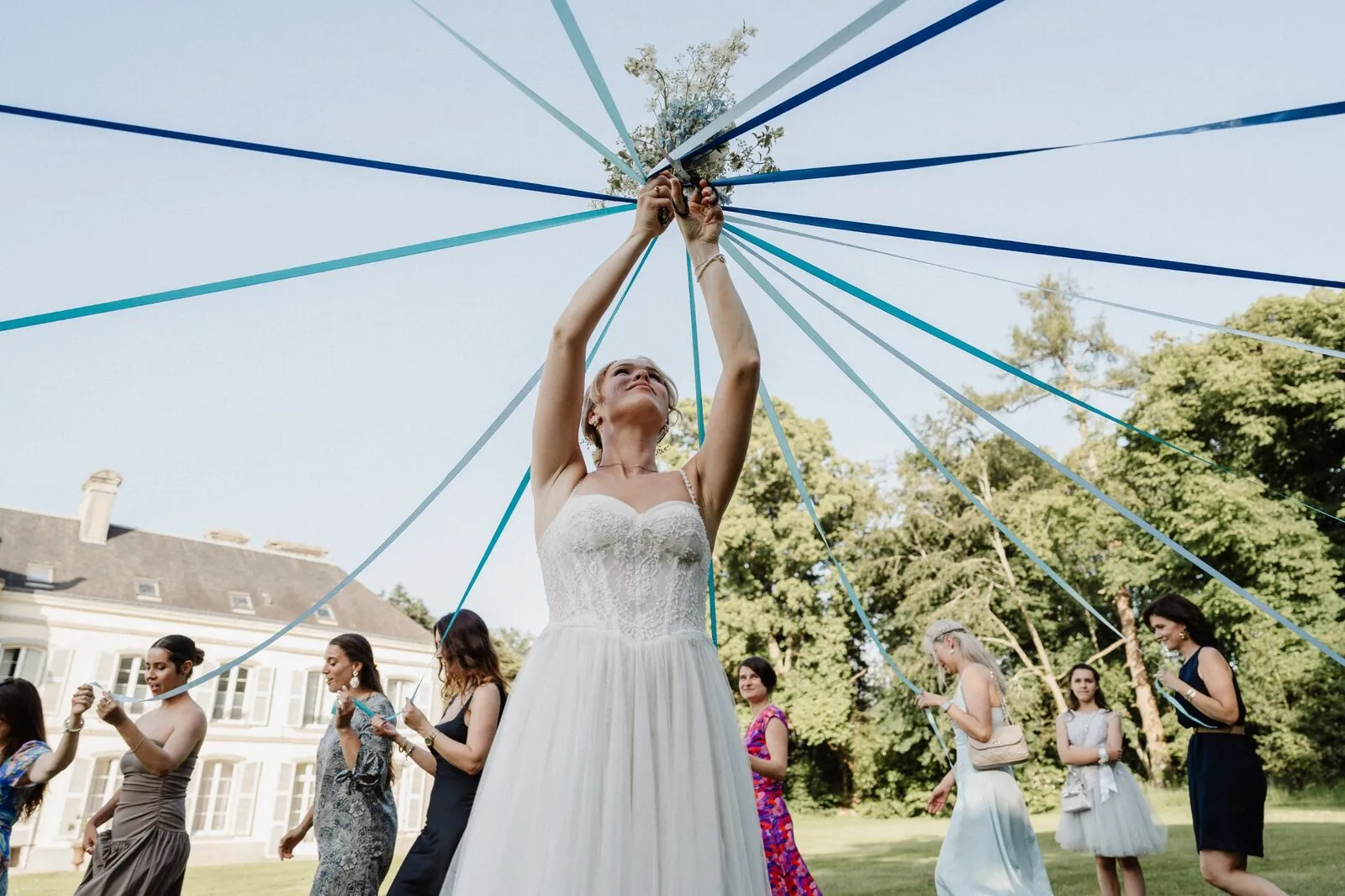 La mariée lance un bouquet relié à des rubans bleus